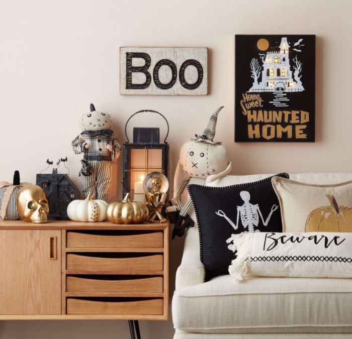 astuces comment décorer sa maison pour Halloween, salon avec canapé blanc et meubles en bois décorés d'objet Halloween noir et or