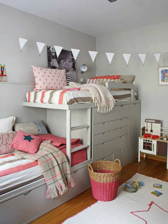 décoration chambre adulte aménager une petite chambre avec deux lits superposés et des drapeaux triangulaires blancs au plafond, tapis blanc avec une étoile rose au sol, coussins et couverture en couleur corail, grande photo de l'enfant au mur