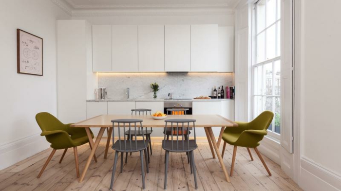comment aménager une petite cuisine blanche avec crédence effet marbre avec éclairage LED, parquet clair, table en bois et chaises vertes et grises