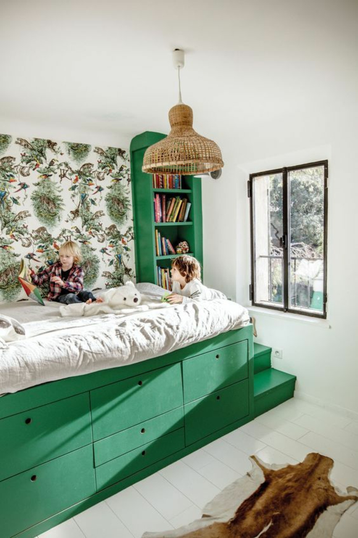 chambre de 9m2 en vert foncé avec lit monté sur une plateforme, sept tiroirs en dessous du lit, petite bibliothèque à côté du lit 
