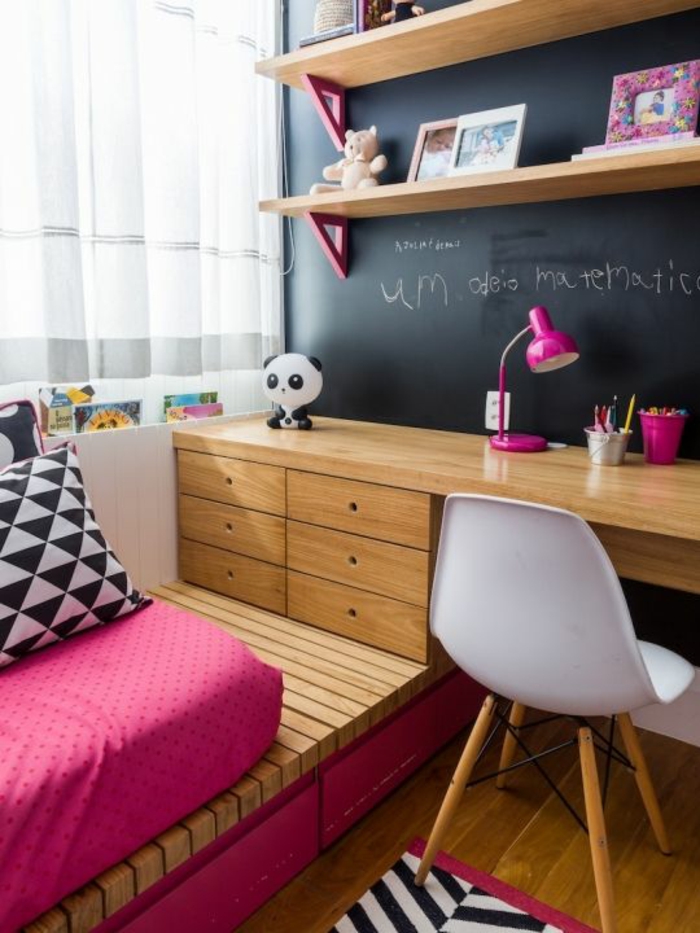 chambre de 9m2 pour enfant avec tableau noir pour écrire, lit sur plate-forme, des tiroirs en bois sur la plate-forme, chaise en plastique blanche sans accoudoirs, avec des pieds en bois clair 