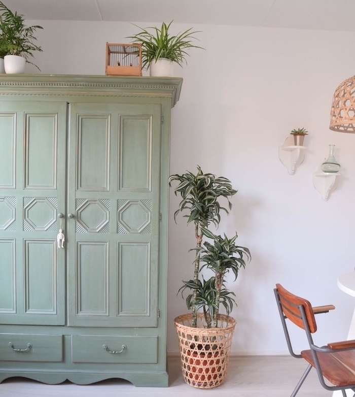 armoire vintage vert pastel, teinte céladon sur le fond d un mir blanc, suspension originale, table blanche et chaises en bois et métal
