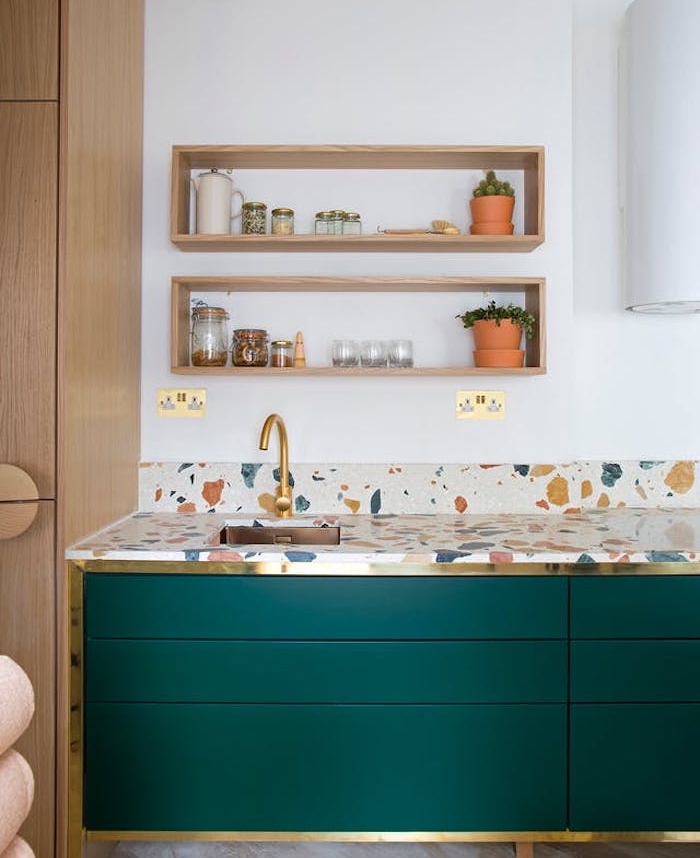 modele de cuisine ancienne avec meuble couleur vert émeraude, plan de travail à taches colorées, robinetterie dorée, étagères en bois ouvertes