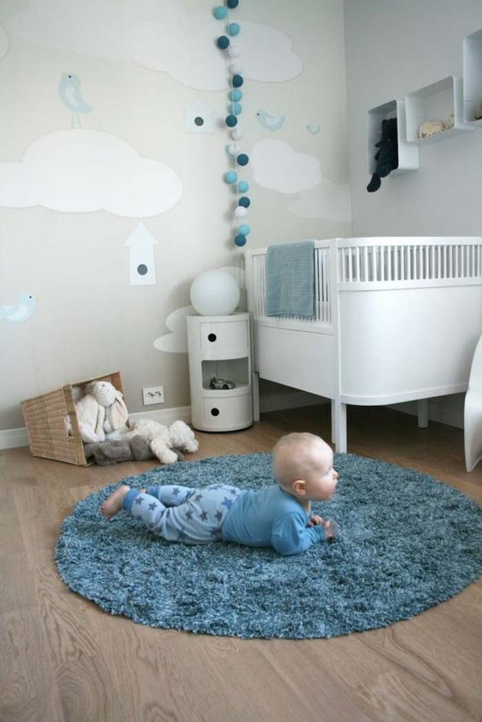 deco chambre bebe garcon avec tapis en forme ronde au milieu de la pièce en couleur bleu canard et déco murale en forme de boules blanches et bleu canard