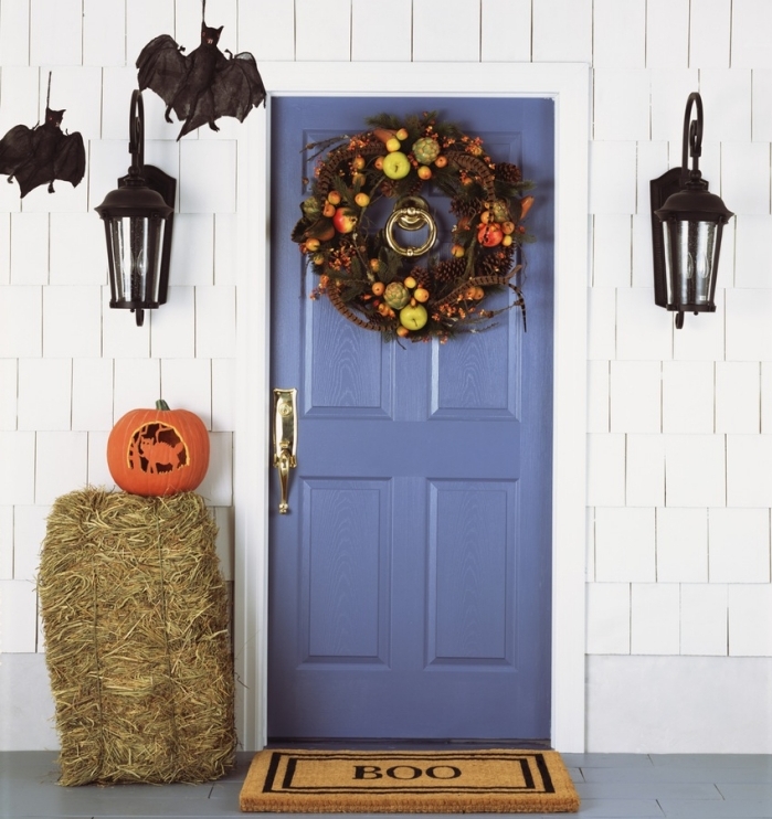 porte d'entrée bleu foncé avec déco halloween en guirlande de fleurs et fruits séchées, lanternes et chauves-souris noirs