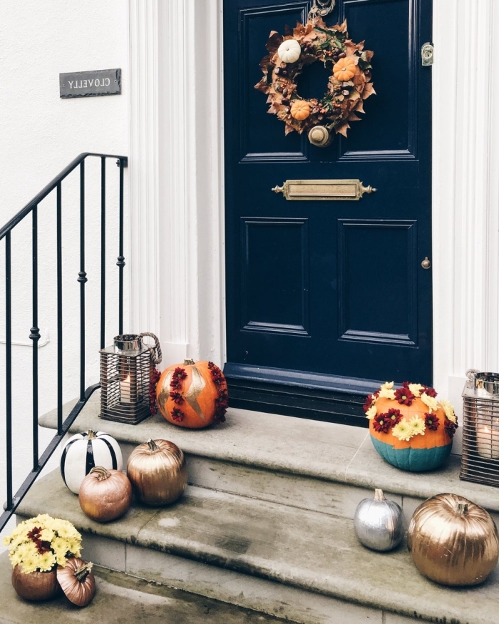 porte d'entrée bleu foncé et façade de maison blanche, guirlande en fruits et feuilles séchées pour Halloween