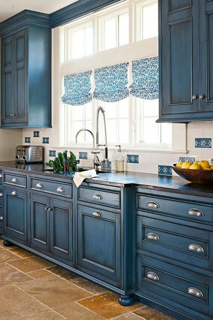 cuisine bleu, meuble bleu canard, des rideaux en bleu et blanc drapés, cadre des fenêtres blancs, carrelage en beige et marron clair, style d' ameublement classique 