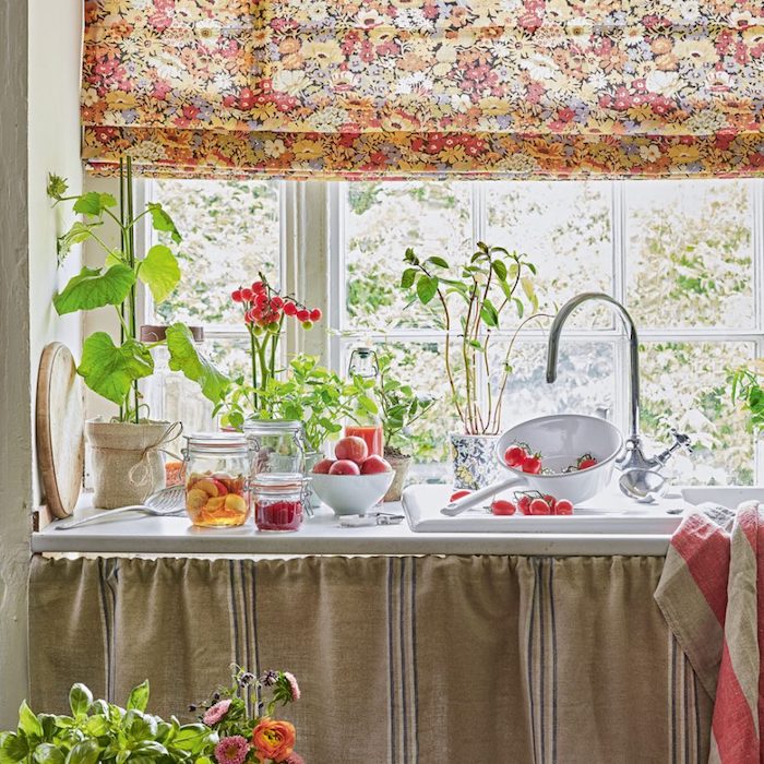 cuisine ancienne, decoration campagne avec plan de travail blanc, voilage à imprimé floral, style shabby chic, fleurs et fruits frais