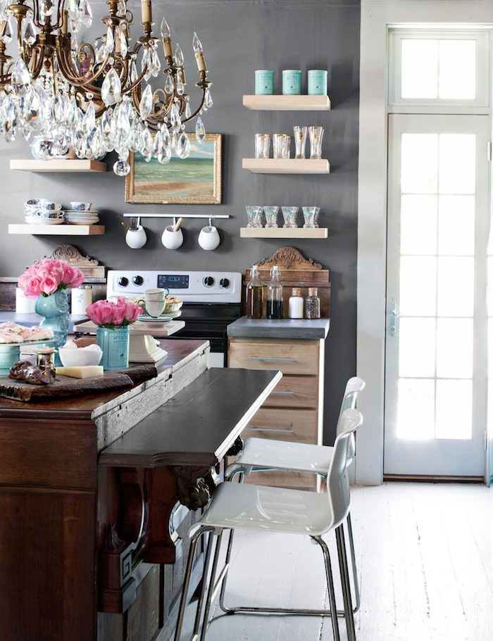 campagne decoration cuisine avec mur gris, décoré d etagres bois avec vaisselle, comptoir bois brut et lustre baroque, chaises blanches