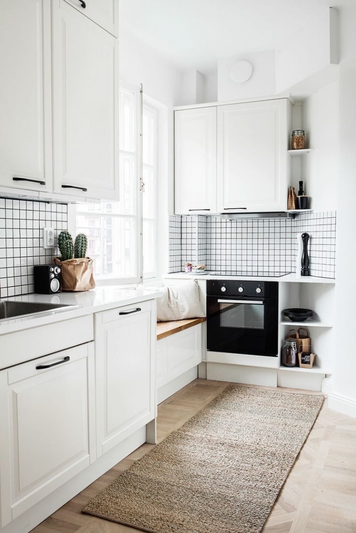 déco scandinave, banc en bois et blanc avec housses blanches au-dessous de la fenêtre, four noire dans cuisine blanche