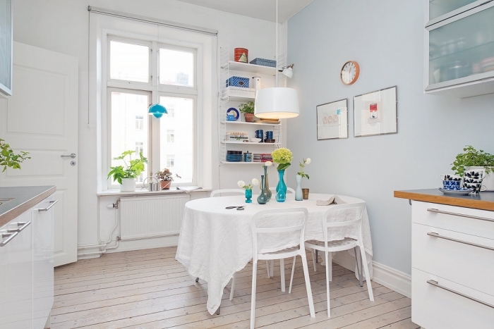 design scandinave, revêtement de sol en bois stratifié avec murs blancs, armoires de cuisine en verre bleu clair