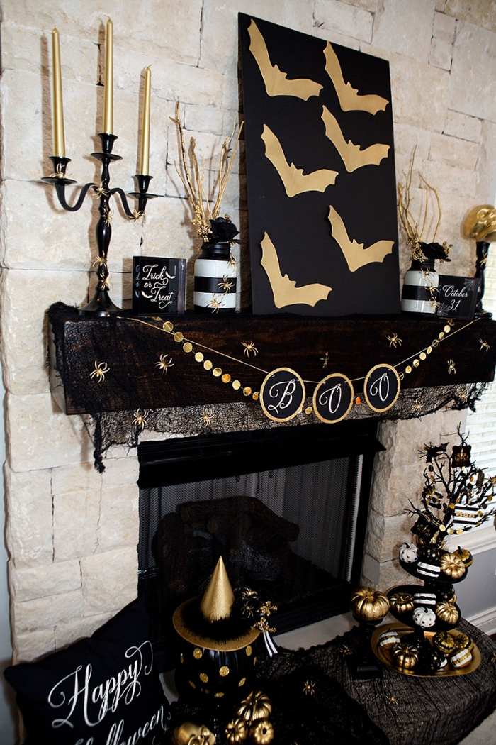 decoration d interieur, salon aux murs en pierre beiges avec cheminée noire décorée en guirlande et objets noir et or pour Halloween