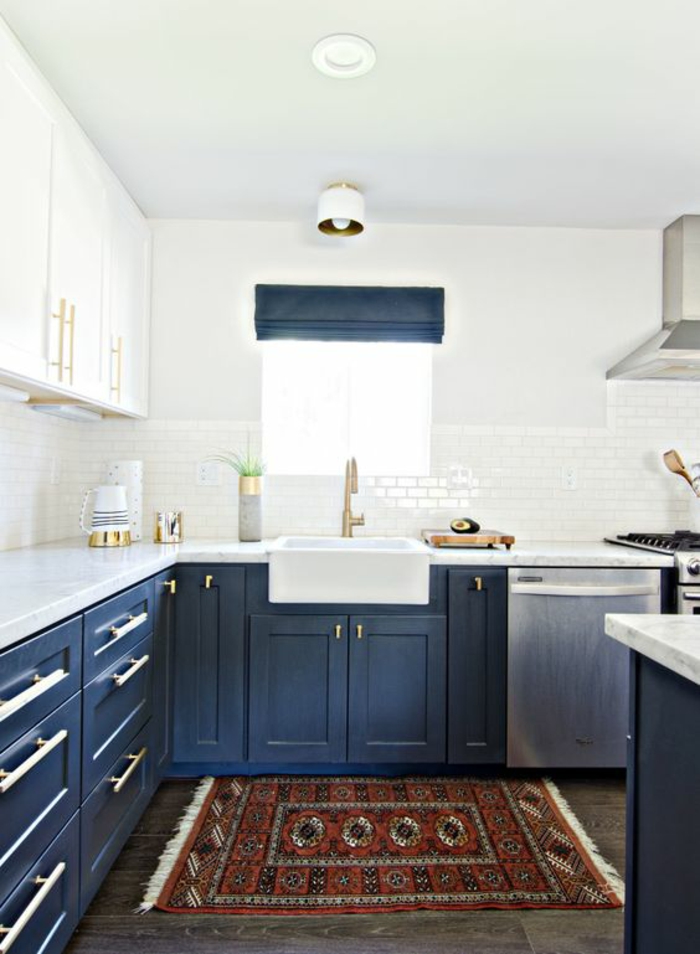 meuble bleu canard, cuisine avec des murs blancs, sol au carrelage en couleur taupe, tapis en couleurs brique, blanc et noir, aspirateur inox, îlot en bleu canard et blanc 