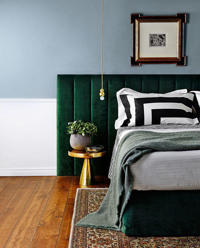 deco chambre adulte avec mur couleur bleue, tête de lit vert emeraude, linge de lit blanc, noir et gris, tapis oriental dessus un parquet marron