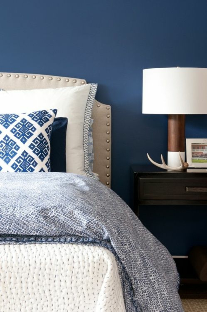 couleur bleu saphir avec dossier de lit en blanc crème et luminaire sur la table de chevet avec abat-jour large en blanc