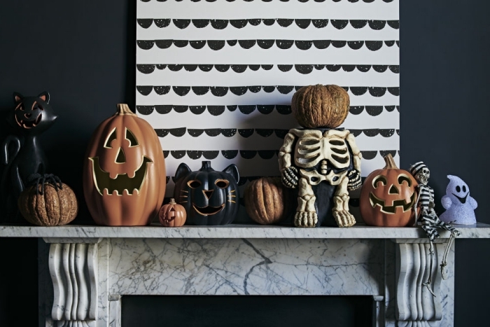 activité halloween, salon aux murs noirs avec cheminée marbre et peinture blanc et noir, figurines décoratives pour Halloween en orange et noir