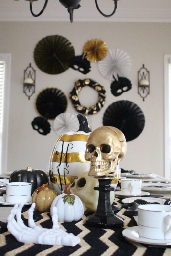 repas halloween, idée comment arranger la table Halloween en blanc noir et or, modèle de citrouille peinte en blanche avec lignes dorées