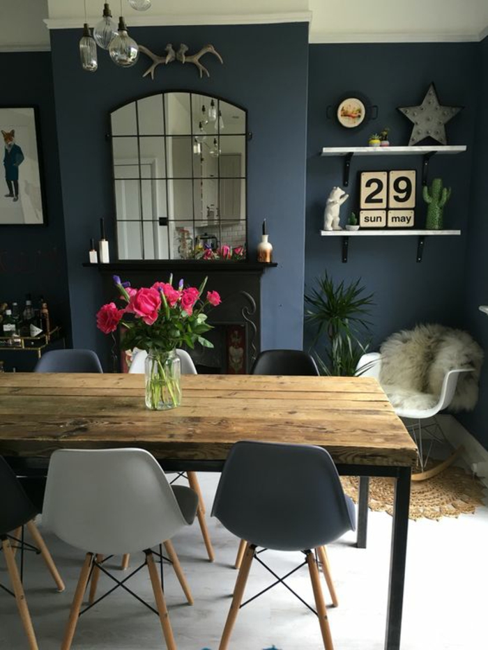 bleu cyan salle à manger ouverte avec grande cheminée noire classique et des chaises en plastique autour de la table en gris foncé et en gris clair