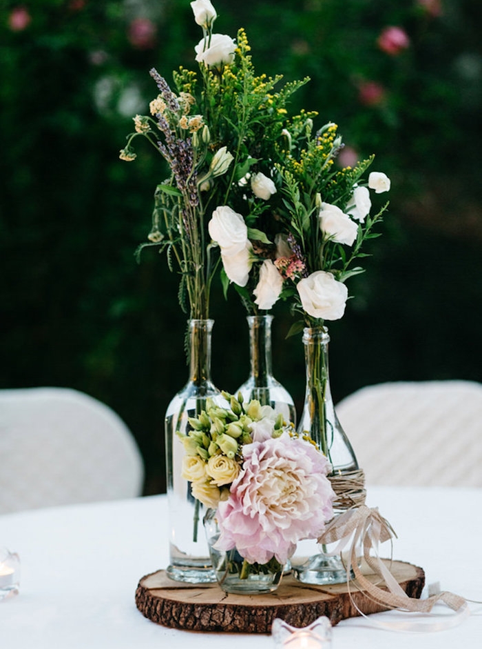 deco table mariage, style champêtre, rondin en bois, bouteilles de vin, enveloppés de ficelle en cuir, bouquet de fleurs