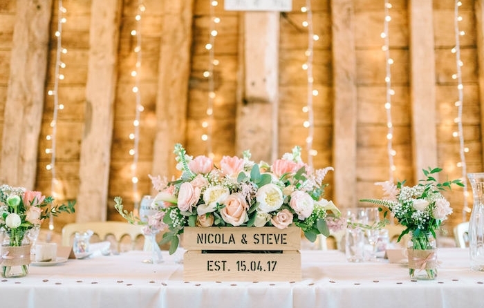 exemple de deco table mariage, nappe blanche, cagette bois fleurie, que faire avec des pots en verre, vases décorés de bandes de jute et ruban, guirlandes lumineuses