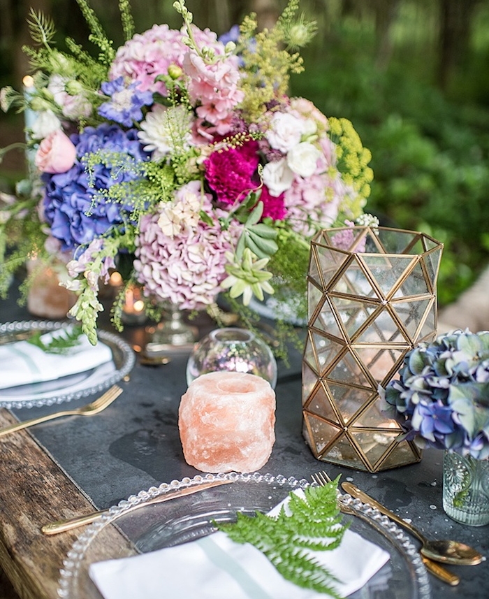 deco table mariage rustique avec des fleurs colorés, rose, fuchsia et violettes, bougies, assiettes en verre et feuille verte dans la serviette