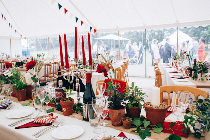 deco table mariage rouge, bougeoir avec des bougies rouges, chemin de table en jute, pots de fleurs, lierre, guirlande fanions