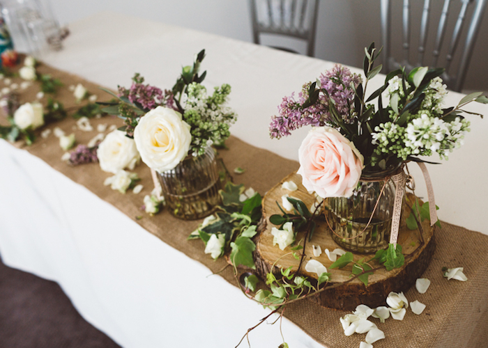 idées décoration mariage à faire soi même, chemin de table en toile de jute, rondin en bois, recyclage pots en verre avec des fleurs champetre