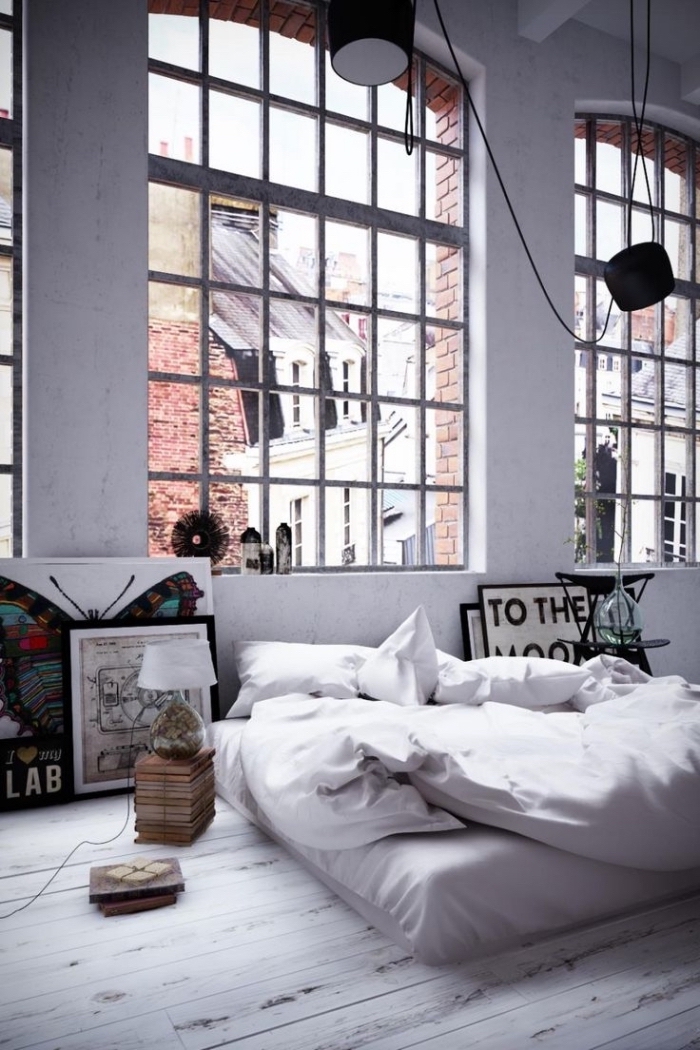 lit industriel bas avec oreillers blancs, peinture à design papillon et poster mots inspirants, chambre loft aux murs blancs