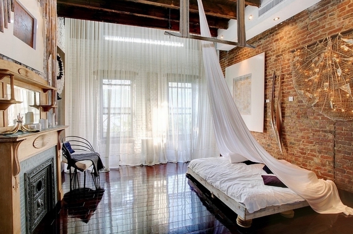 intérieur de chambre à coucher à design loft industriel aux murs en briques et plafond en poutres marron foncé