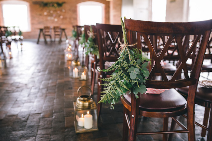 decoration mariage champetre pour la salle de mariage, mur en pierre, lanternes avec des bougies, chaises en bois fleuris