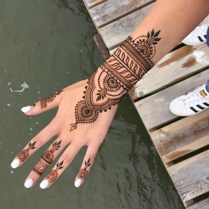 modele henné main, manucure aux ongles blancs, tatouage au henné noir à design ethnique pour femme
