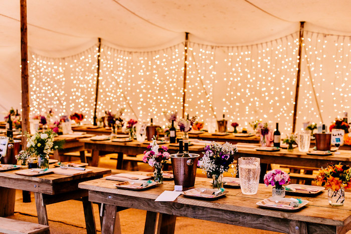 mariage champetre chic, tables et bancs en bois, pots en verre fleuris, décoration de guirlandes lumineuses, chapiteau mariage