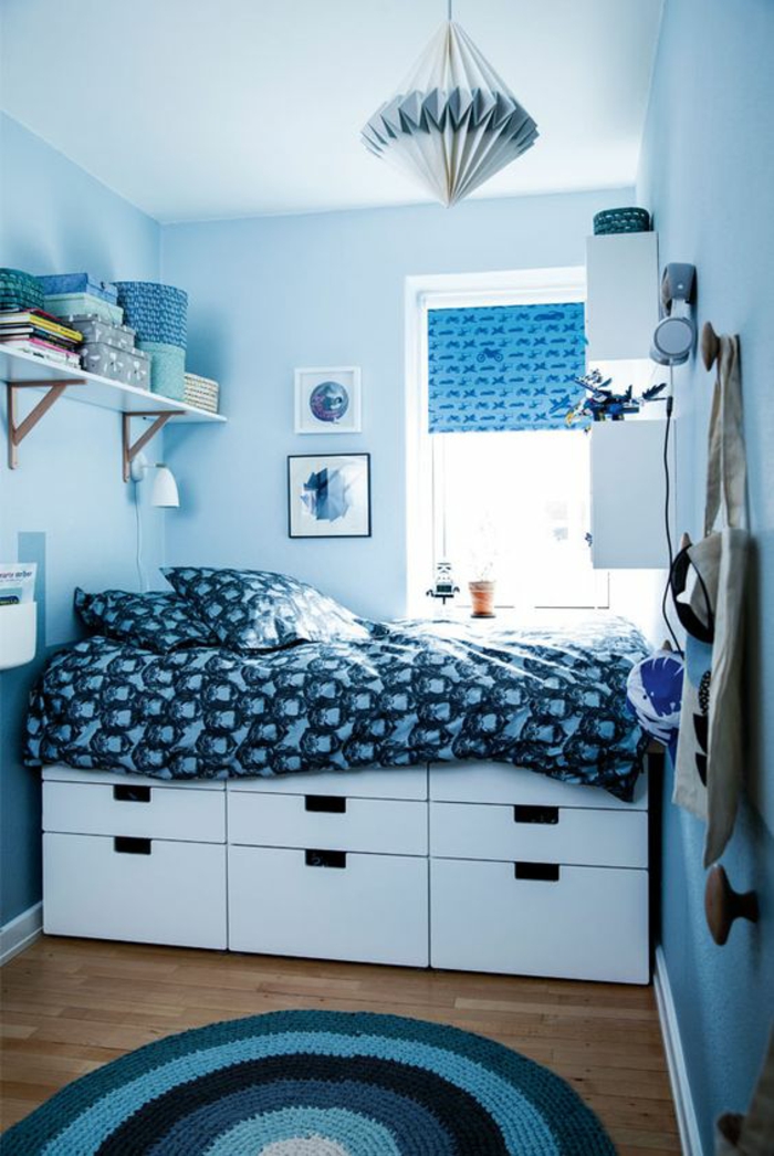 aménager une chambre de 10m2 en bleu azur, lit avec des grands tiroirs en dessous, avec couverture en bleu et blanc, luminaire en carton en bleu et blanc en forme conique, tapis rond en azur, blanc et noir