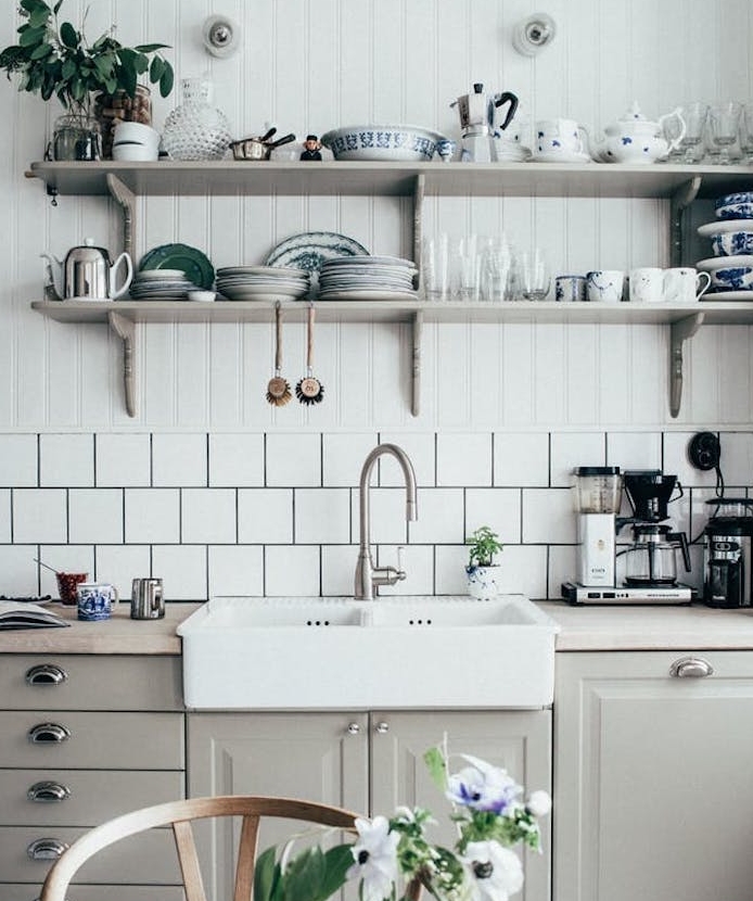 modele de cuisine campagnarde avec façade gri perle, poignées vintage, crédence carrelage blanc, etageres en bois avec vaisselle vintage, plantes vertes