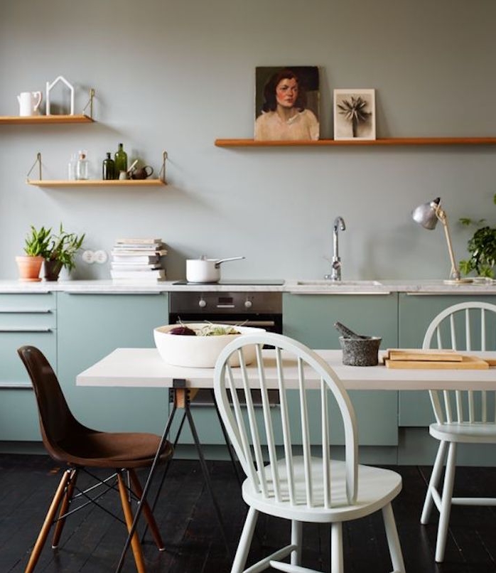 facade cuisine bleu celadon, table salle à manger en noir et blanc, chaises blanches et chaise marron, étagères en bois