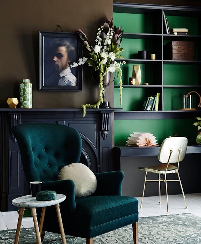 fauteuil couleur bleu pétrole, cheminée grise, bibliothèque avec fond vert, tapis gris et vert clair vintage, portrait peinture cadre retro