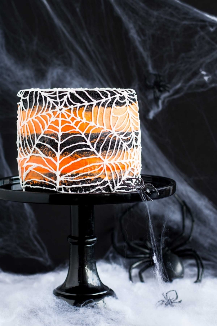 fete halloween, idée pour un gâteau style Halloween au glaçage rayé en orange et noir avec décoration sucrée en forme de toile d'araignée