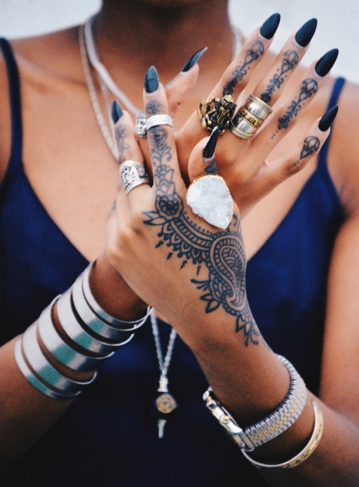 henné tatouage, femme avec bijoux métalliques collier bracelet montre et bagues, mains féminins au vernis noirs et tatouage temporaire