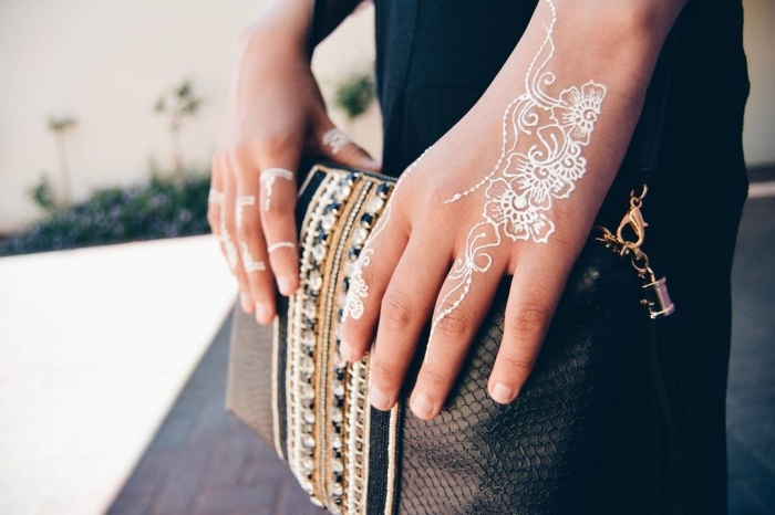 modele henné, tatouage temporaire au henné blanc à design florale sur les doigts, modèle de pochette noire avec décoration en dentelle