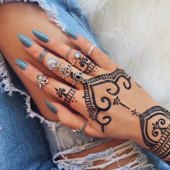 modele henné main, manucure aux ongles longs et vernis bleu foncé, bijoux métalliques et tatouage ethnique