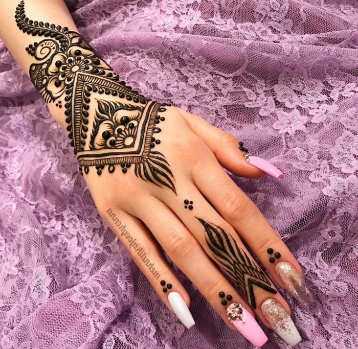 modele henné main, dessin sur la main et les doigts au henné noir, tatouage temporaire à design ethnique