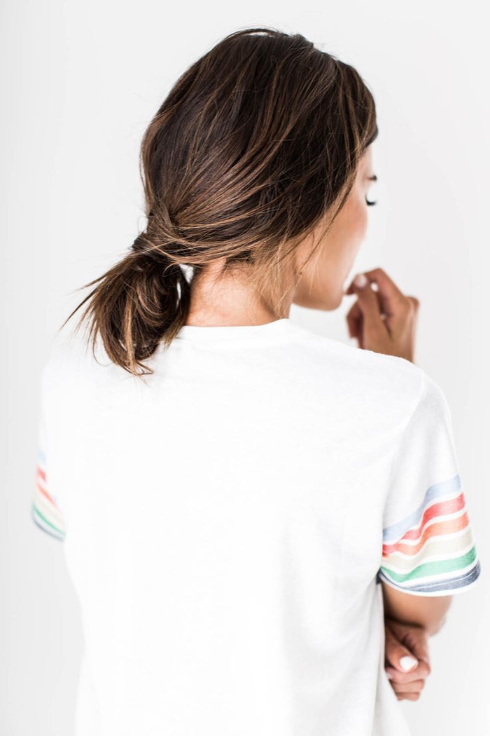 idées-coiffures-cheveux-mi-long-chignon-bas-flou-queue-de-cheval-décoiffée-t-shirt-manche-rayée une coiffure simple et rapide à effet coiffé-décoiffé avec un chignon bas et fluide