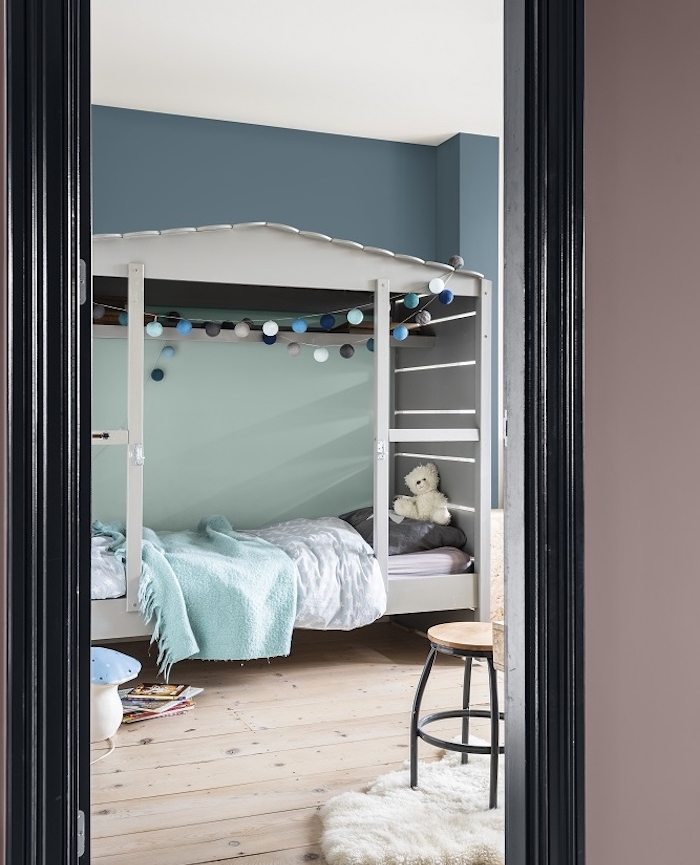 comment amenager une chambre enfant, peinture murale bleu gris avec un pan de mur vert céladon, lit cabane gris, parquet clair, linge de lit bleu et gris, design scandinave