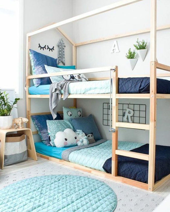 deco chambre bebe garcon en bleu canard avec des lits superposés en bois clair avec plein de coussins en vert canard et bleu canard