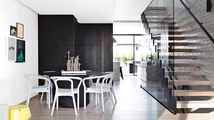 comment aménager une cuisine en longueur cuisine grise avec bar en marbre ouverture sur une salle à manger avec table ronde noire et chaises blanches, escalier en bois