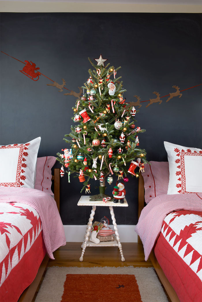 exemple de décoration sapin de noel en ornements rouges et blancs, motif père noel, petites figurines festive, deux lits avec linge de lit rouge et blanc