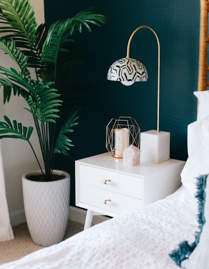idée de déco chambre à coucher design scandinave avec un mur de fond peinture bleu paon, table de nuit avec tiroirs blanche, linge de lit blanc, tapis gris, lampe bougie, palmier vert