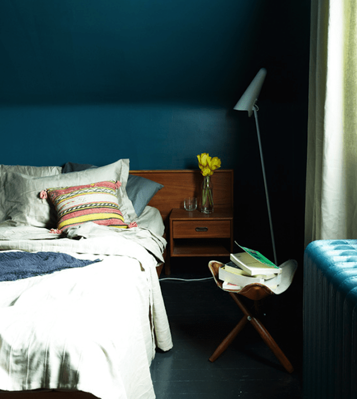 bleu petrole peinture pour une chambre sous pente, linge de lit gris, table de nuit en bois, parquet gris anthracite, tabouret rangement de livres