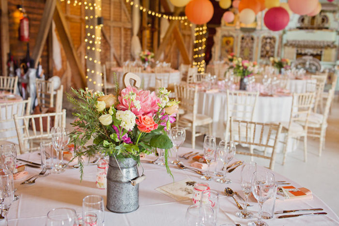 mariage champêtre, nappe blanche, pot à lait rempli de fleurs champetre, lanternes colorées et guirlande lumineuse