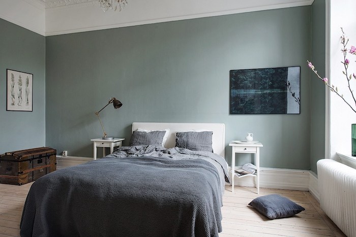 murs couleur vert de gris dans une chambre à coucher adulte design, parquet en bois clair, linge de lit gris, coffre de rangement vintage, chambre scandinave